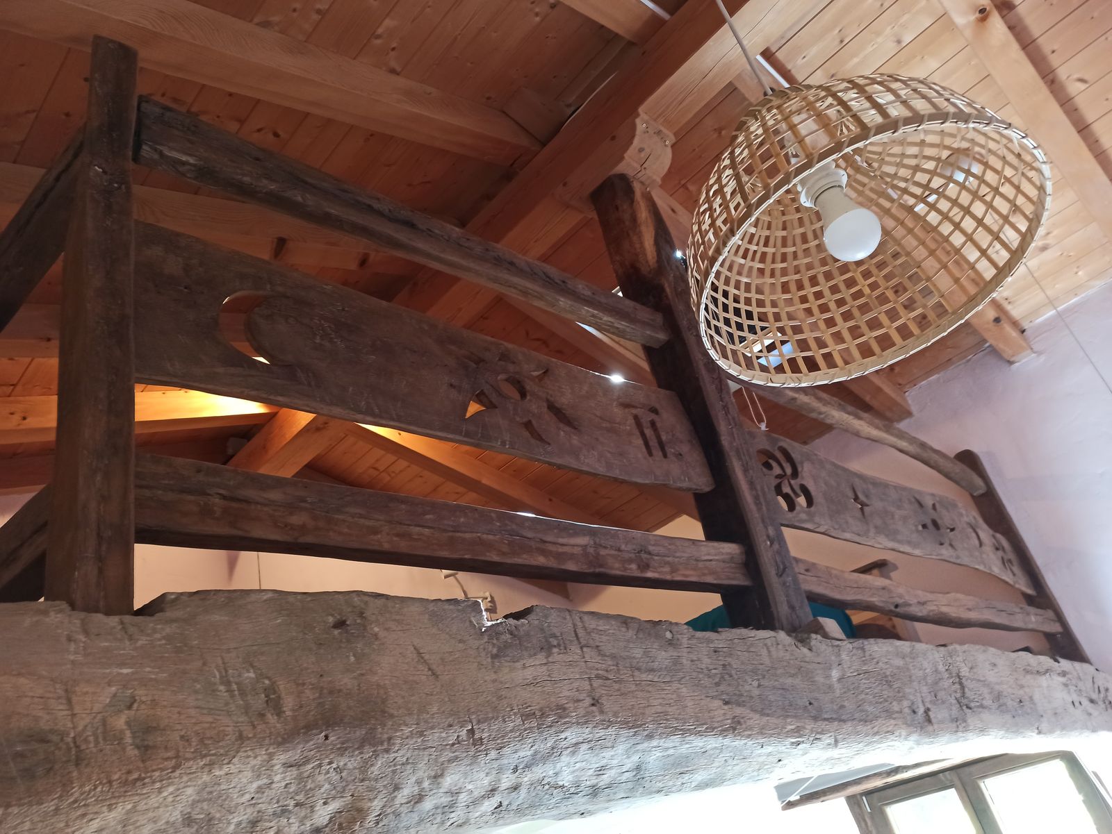 Vigas de madera originales y lámpara de mimbre en la casa rural TTipiaenea